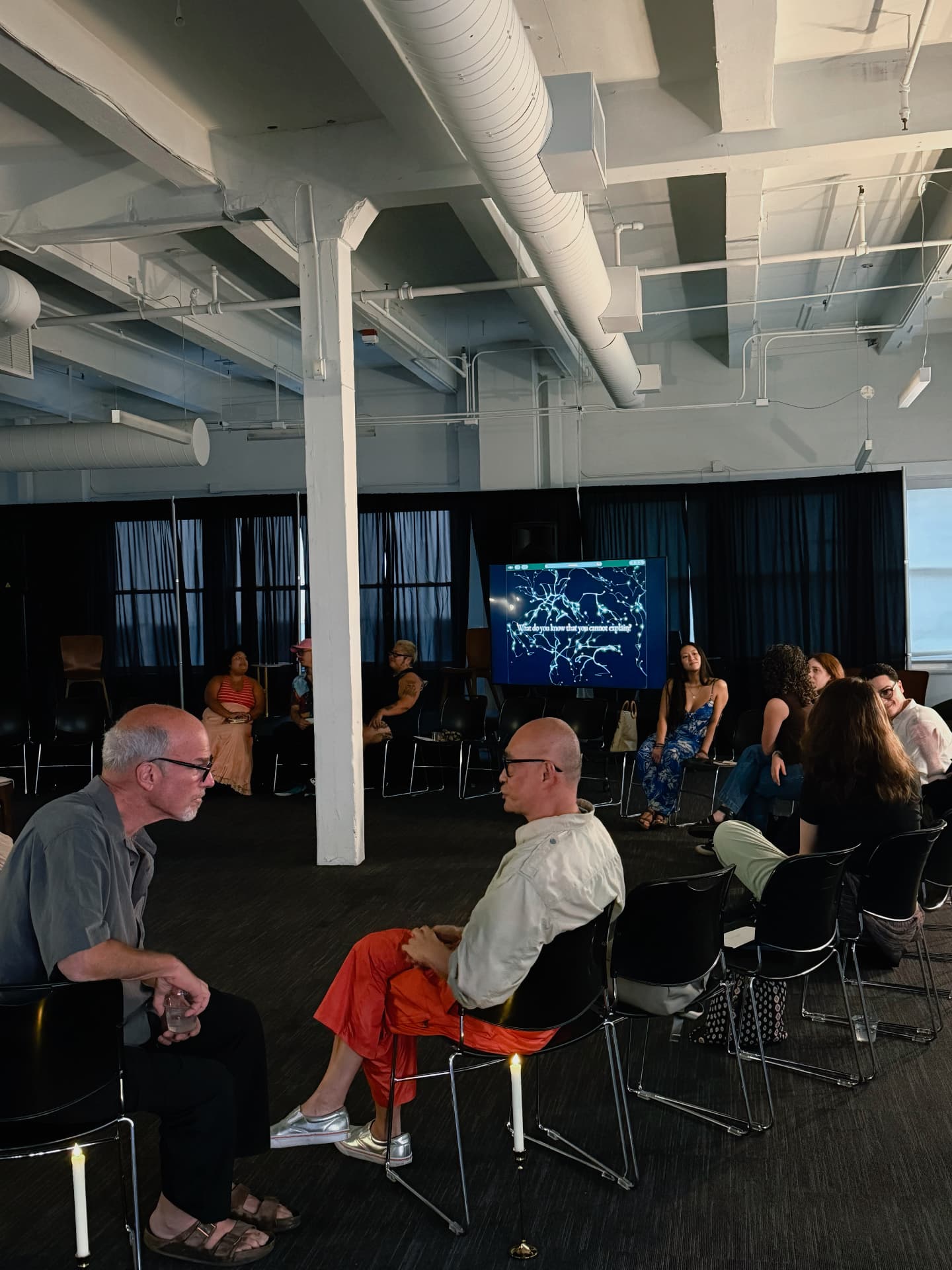 Guests seated in conversation with the question glowing on screen